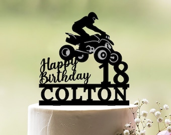 May include: Black cake topper featuring a silhouette of a person riding a quad bike, with the words "Happy Birthday Colton" and the number "18" on the bottom.