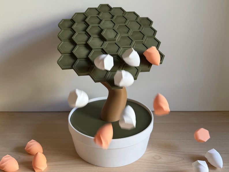 May include: A whimsical, modern bonsai tree sculpture with a green hexagonal canopy and a brown trunk, set in a white pot. White and peach-colored objects appear to be falling from the tree, creating a dynamic visual.