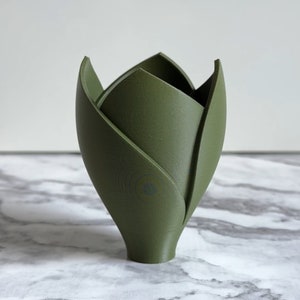 May include: A green ceramic vase shaped like a tulip with a rounded base.