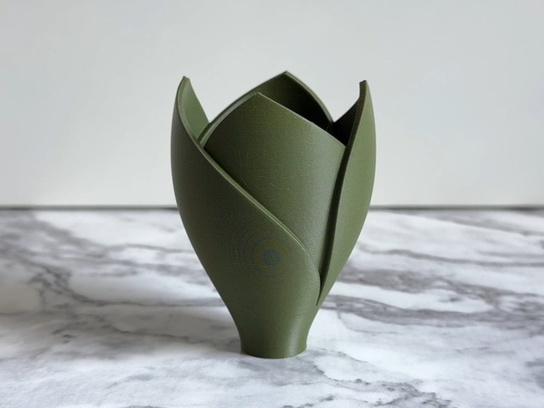 May include: A green ceramic vase shaped like a tulip with a rounded base.