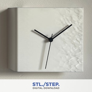 Può includere: Orologio da parete quadrato bianco con lancette nere. Il quadrante dell'orologio ha una superficie testurizzata.