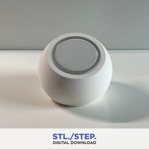 May include: A white, round, 3D printed object with a silver ring around the top. The object has a smooth, matte finish.