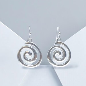 May include: A pair of silver-toned drop earrings featuring a circular spiral design. Each earring is suspended from a simple hook wire, showcasing a polished metallic finish with a continuous, open-work swirl pattern that creates a balanced look.