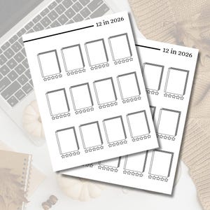 May include: Two white paper sheets with a book reading tracker design. Each sheet has 12 book outlines with star rating sections and the text "12 in 2026". The sheets are on a white surface near a laptop.