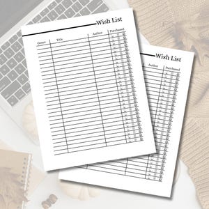 May include: Two white "Wish List" sheets with black lines and text, including "Genre," "Title," "Author," and "Purchased." The sheets are on a white surface near a laptop keyboard and a notebook.