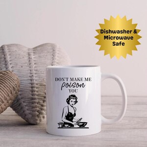 May include: White ceramic mug with a black graphic of a woman cooking and the text "DON'T MAKE ME poison YOU". A gold starburst graphic indicates the mug is dishwasher and microwave safe.