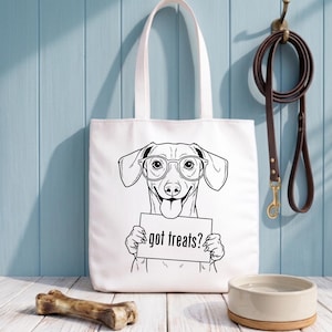 Op de afbeelding: Witte draagtas met een zwart-wit illustratie van een teckel met een bril en een bord met de tekst "got treats?". Een hondenriem en een kom zijn ook zichtbaar.