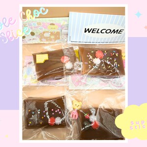 May include: Three individually wrapped chocolate squares with different toppings, including sprinkles, chocolate chips, and a red and white swirl. The squares are labelled "Triple Choc Slice" and "Super Sticky".