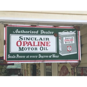 May include: A vintage metal sign advertising Sinclair Opaline Motor Oil. The sign is green, red, and white with the text "Authorized Dealer Sinclair Opaline Motor Oil" and "Seals Power at every Degree of Wear".