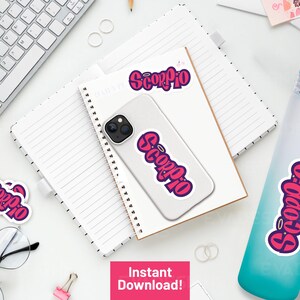 May include: A collection of stickers, a phone, and a water bottle, all featuring the word "Scorpio" in a pink and purple design. The stickers are scattered on a white surface with notebooks, a keyboard, and other office supplies.