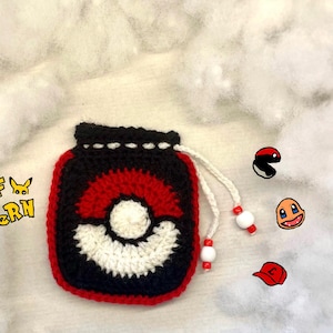 Könnte beinhalten: Eine rote, weiße und schwarze gehäkelte Pokeball-Kordeltasche mit einer weißen Schnur und weißen Perlen. Die Tasche befindet sich auf einer weißen, flauschigen Oberfläche.  PDF PATTERN.