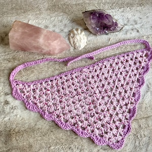 Detailed view of the handmade crochet work on the Aphrodite Shell Hair Bandana, highlighting the fine craftsmanship and unique shell edge. The color option is Peony, a pink multicolored triangle with purple edging and ties.