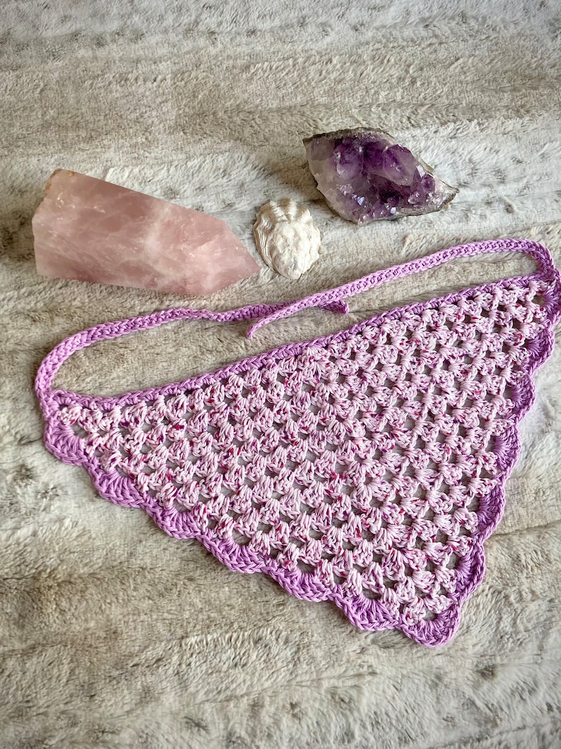 Detailed view of the handmade crochet work on the Aphrodite Shell Hair Bandana, highlighting the fine craftsmanship and unique shell edge. The color option is Peony, a pink multicolored triangle with purple edging and ties.