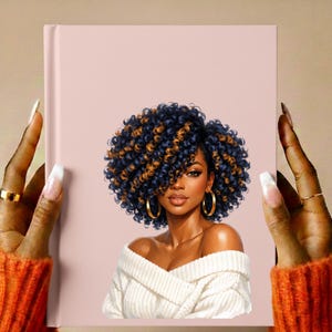 May include: A pink journal with an illustration of a woman with blue and gold curly hair, gold hoop earrings, and a white off-the-shoulder sweater. The journal is held by hands with long, manicured nails and gold rings.
