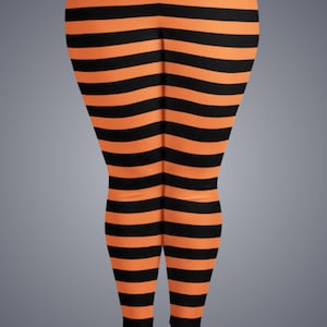 May include: Leggings featuring a repeating horizontal striped pattern in alternating black and bright orange colors. The garment covers the legs from the upper thigh down to the ankles, displaying a consistent, uniform stripe width throughout the design.