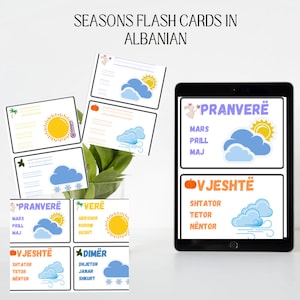 May include: Flash cards for learning the seasons in Albanian. The cards feature illustrations of the sun, clouds, and weather associated with each season. The Albanian words for each season are written in large, colorful letters.