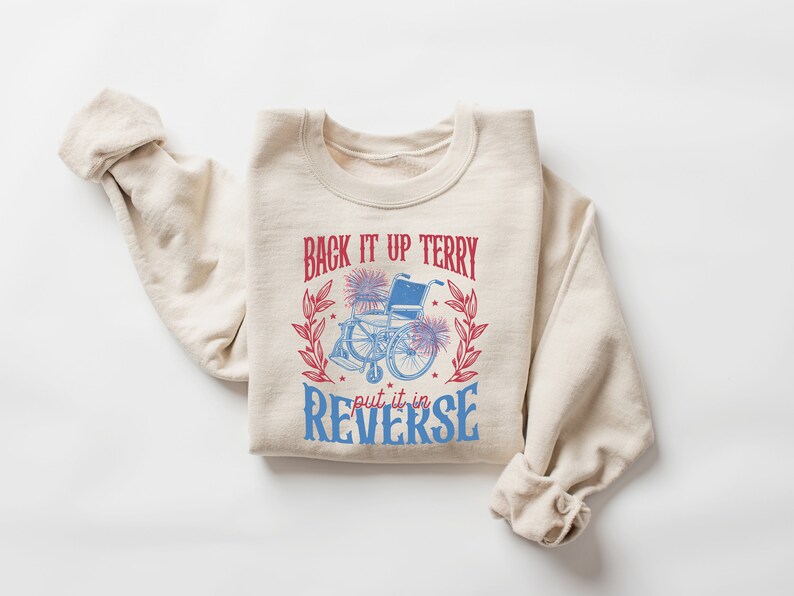 May include: A beige sweatshirt with a graphic print of a wheelchair with fireworks and the text "Back it up Terry put it in reverse".
