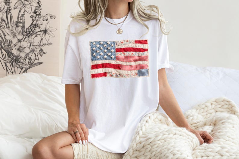 Peut inclure: T-shirt blanc avec un drapeau am&eacute;ricain en patchwork. Le drapeau utilise des tissus rouges, blancs et bleus avec des motifs floraux et vichy. Le t-shirt est de style d&eacute;contract&eacute; &agrave; manches courtes.