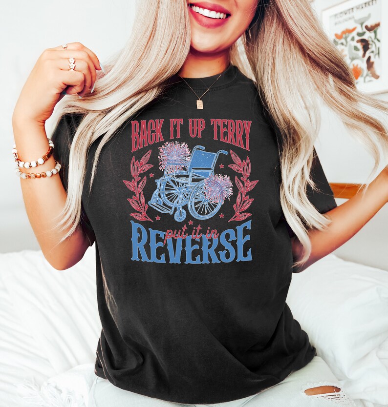 May include: Black t-shirt with a red and blue graphic design featuring a wheelchair with flowers and the text "Back it up Terry put it in reverse."