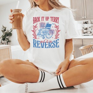 May include: White t-shirt with a red and blue graphic of a wheelchair with the text "Back it up Terry put it in reverse".