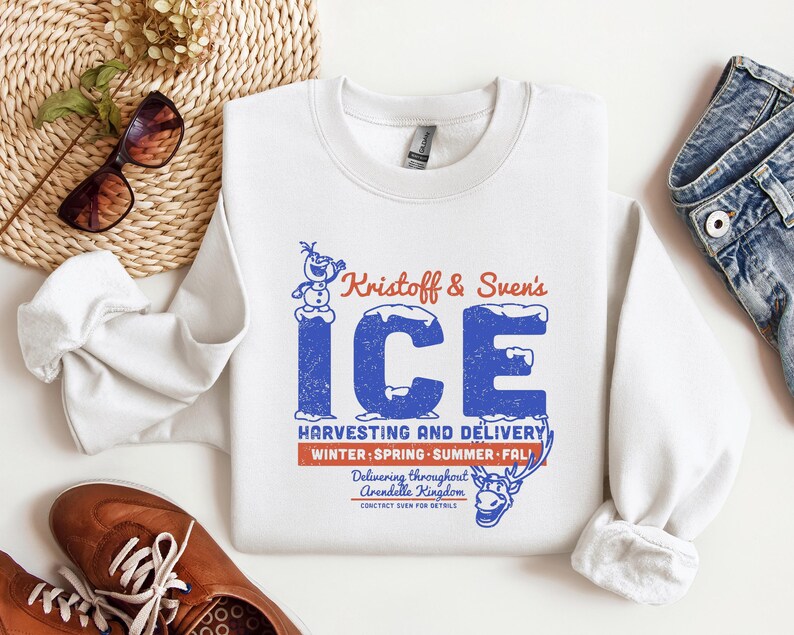 May include: White crewneck sweatshirt with a blue and red graphic. The graphic reads "Kristoff & Sven's ICE" with text below indicating "Harvesting and Delivery" and "Winter, Spring, Summer, Fall".
