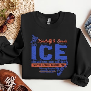 May include: Black crewneck sweatshirt with the text "Kristoff & Sven's ICE" in blue and orange. The graphic includes a snowman and reindeer, with the words "Harvesting and Delivery" and "Winter, Spring, Summer, Fall".