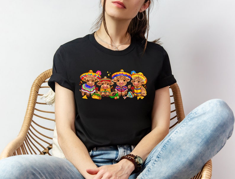 May include: Black t-shirt with a graphic of four brown cows wearing colorful sombreros and holding maracas. The cows are wearing traditional Mexican clothing.