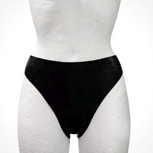 Puede incluir: Bragas negras de cintura alta. La ropa interior está hecha de un material liso y brillante. El diseño de cintura alta cubre la parte inferior del abdomen. La ropa interior se muestra en un maniquí blanco.