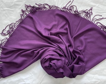 May include: A purple scarf with fringe on all sides. The scarf is made of a soft, lightweight fabric.