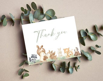May include: A white thank you card with a green handwritten "Thank you" message. The card features a watercolour illustration of a group of woodland animals, including a deer, a fox, a raccoon, and a rabbit.