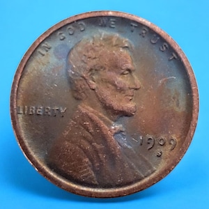Puede incluir: Un centavo de cobre de 1909 con las palabras "In God We Trust" y "Liberty" visibles. La moneda presenta un perfil de Abraham Lincoln.