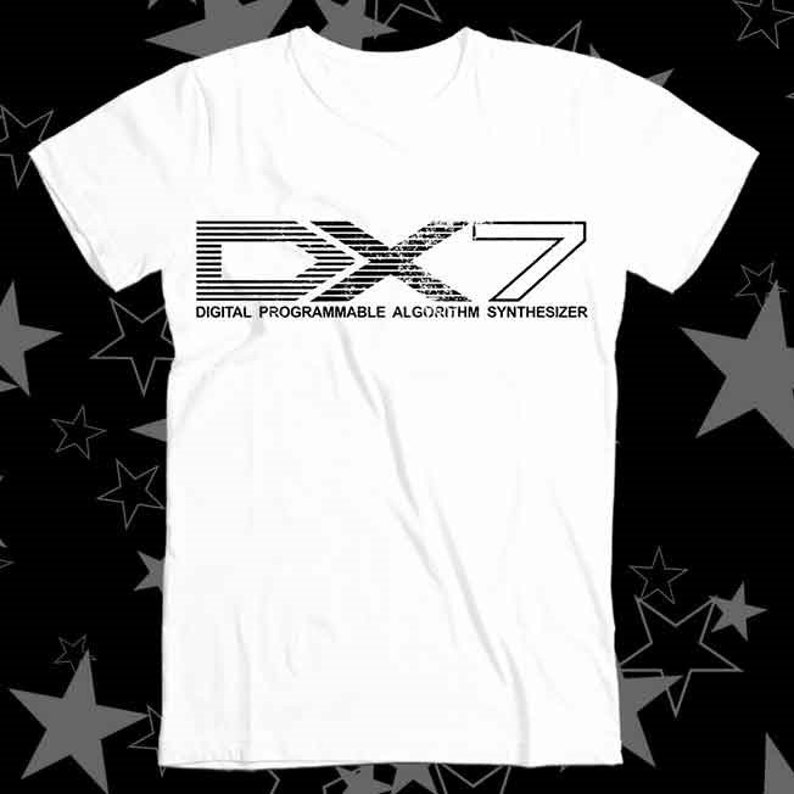 K&ouml;nnte beinhalten: Wei&szlig;es T-Shirt mit einer schwarz-wei&szlig;en Grafik des Textes "DX7" und den Worten "DIGITAL PROGRAMMABLE ALGORITHM SYNTHESIZER" darunter.