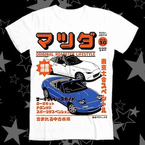 May include: A white t-shirt with a vintage magazine cover design featuring a red and orange Japanese word "マツダ" (Mazda) and a white and blue roadster car. The magazine cover text reads "ORIGINAL ROADSTER LIFESTYLE" and "東京大会スペシャル" (Tokyo Tournament Special).