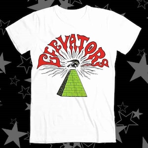 May include: White t-shirt with a red "Elevators" logo featuring an all-seeing eye over a green pyramid.