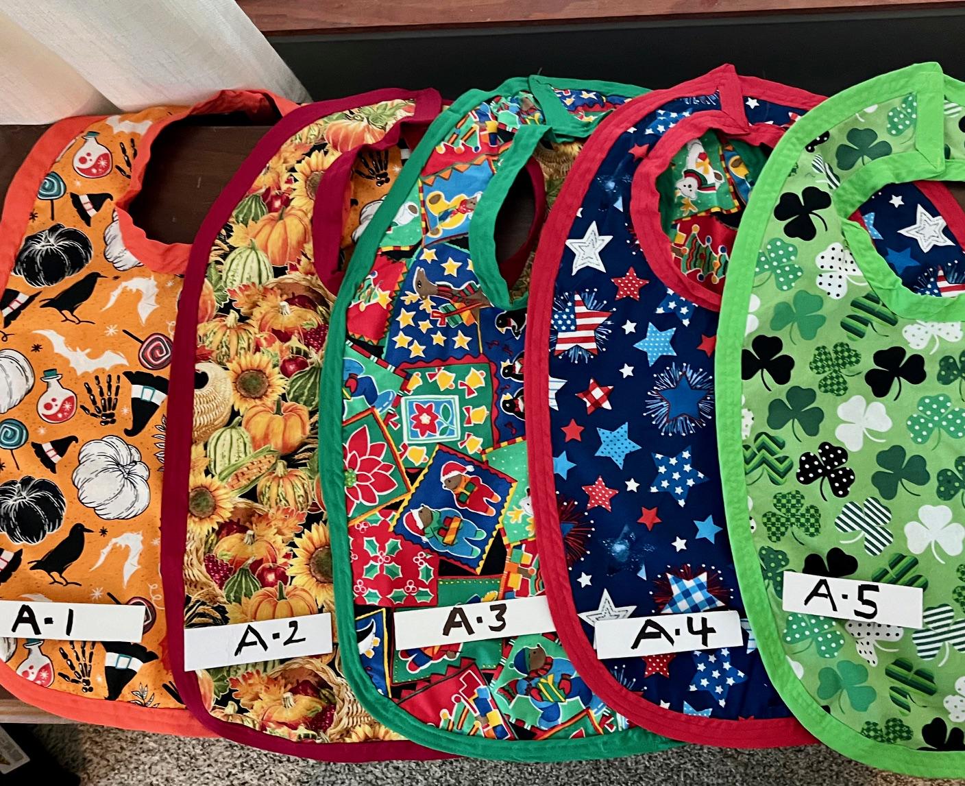 Large Bibs for Seniors  in varied themed patterns.  Hand made, double sided w/different patterns and accent edge binding