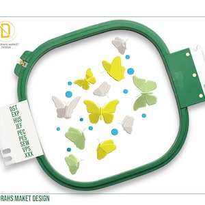 May include: An embroidery hoop with a butterfly design. The butterflies are in shades of yellow, green, and gray, with blue dots scattered around them. The text "DEBORAHS MARKET DESIGN" is visible.