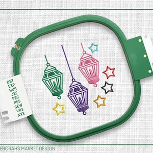 Può includere: Disegno di ricamo di tre lanterne colorate con stelle, mostrato in un telaio da ricamo verde. Il disegno include il testo "DST, EXP, HUS, JEF, PEC, PES, SEW, VP3, XXX".