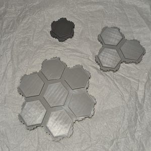 May include: A set of six gray hexagonal tiles, with a smaller gray hexagonal tile and a three-piece gray hexagonal tile.