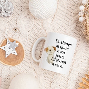 Puede incluir: Taza de caf&eacute; de cer&aacute;mica blanca con una ilustraci&oacute;n en blanco y negro de un perro y el texto "Do things at your own pace. Life's not a race."