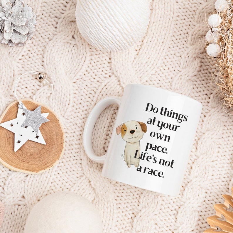 Puede incluir: Taza de caf&eacute; de cer&aacute;mica blanca con una ilustraci&oacute;n en blanco y negro de un perro y el texto "Do things at your own pace. Life's not a race."