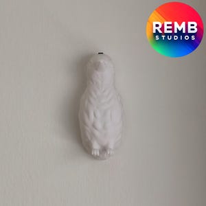 K&ouml;nnte beinhalten: Wei&szlig;e Keramik-Pinguin-Figur mit strukturierter Oberfl&auml;che. Der Pinguin schaut nach oben mit ausgebreiteten Fl&uuml;geln.