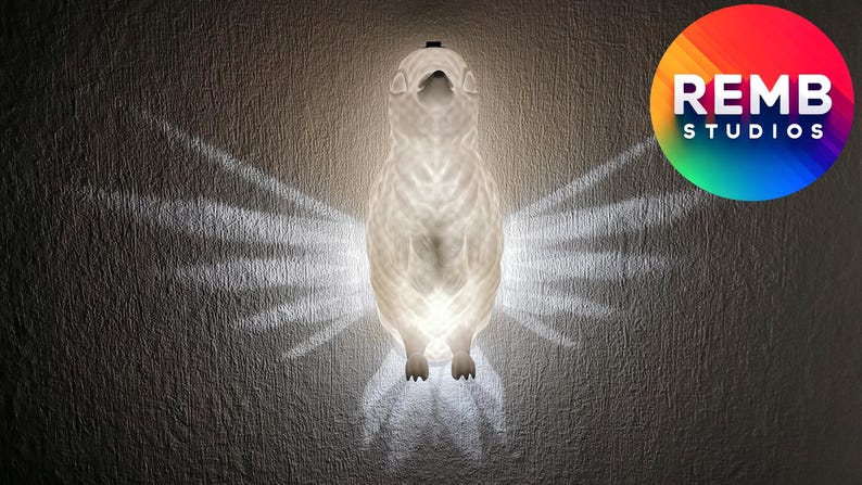 K&ouml;nnte beinhalten: Eine wei&szlig;e Keramik-Eulen-Nachtlampe mit einem leuchtenden Licht, das aus ihrem K&ouml;rper strahlt. Die Eule sitzt an einer Wand mit einem Schatten ihrer Fl&uuml;gel dahinter.