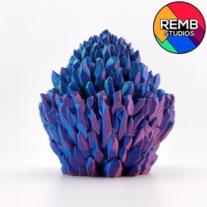 May include: A 3D-printed sculpture of a cluster of crystalline structures. The sculpture features a gradient of colors, transitioning from deep purple at the base to vibrant blue at the tips. The overall shape is roughly conical, with sharp, angular facets.
