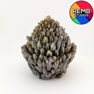 May include: A 3D-printed sculpture resembling a cluster of crystals. The sculpture is primarily dark gray with hints of gold and green. The base is bowl-shaped, and the crystals rise to a point. The logo for REMB STUDIOS is in the upper right corner.