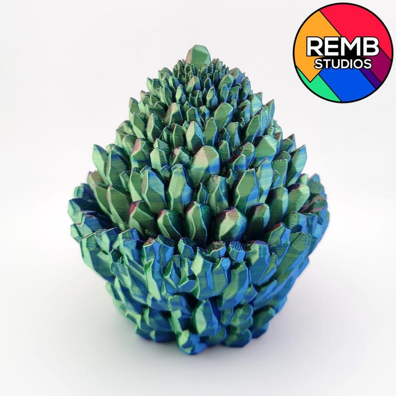May include: A 3D-printed sculpture resembling a cluster of crystals. The piece features a gradient of blue and green hues, with a textured surface. The sculpture has a rounded base and a pointed top, and is set against a white background.