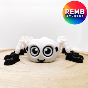 May include: White spider toy with black boots and large eyes. The toy has a friendly expression and is made of plastic.