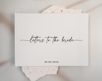 May include: A white rectangular book with the text "letters to the bride" in black cursive script centred on the front cover. Below the text, the date "28.08.2026" is printed in a simple black sans-serif font on the lower portion.