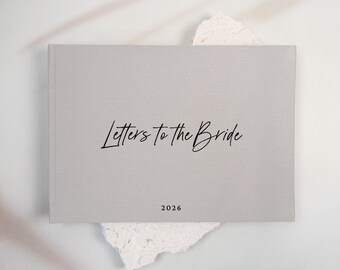 May include: A rectangular, light gray, fabric-covered book with the text "Letters to the Bride" in a black script font centered on the front cover, with the year "2026" printed in a smaller, simple black font below the main title.