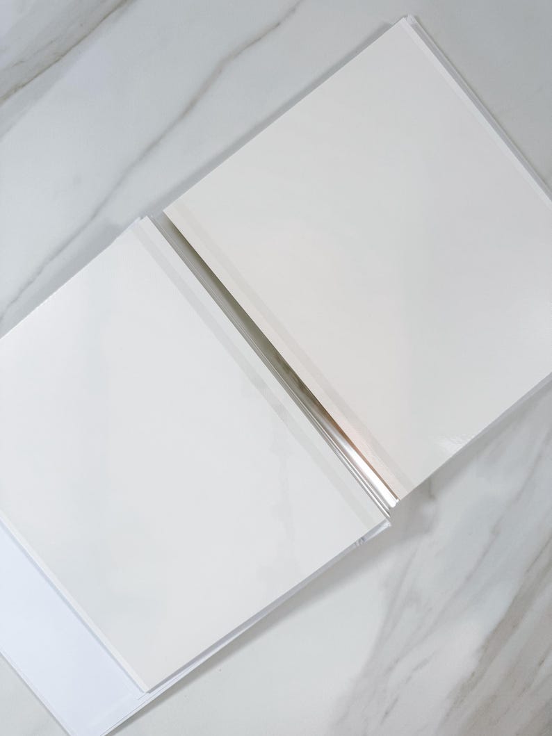 two white rectangular books lying on a marble surface.