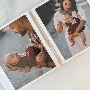 A photo album with two pages featuring a woman holding a baby, both smiling and looking at the camera.